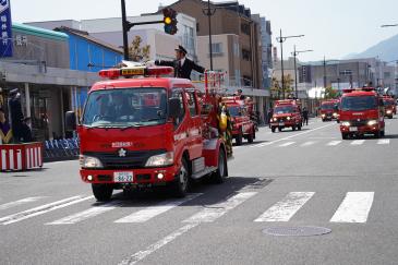 消防団に続き大通りを行進する消防車両