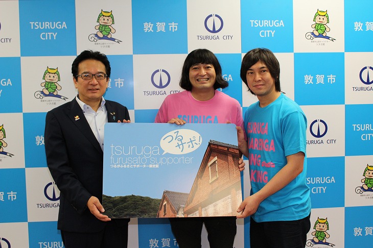 つるサポ認定証を持つハイキングウォーキングと渕上市長（左から渕上市長、鈴木Ｑ太郎さん、松田洋昌さん）