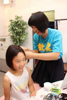 小学生にヘアアレンジをする高校生