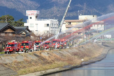 ポンプ車から勢いよく放水する消防団員