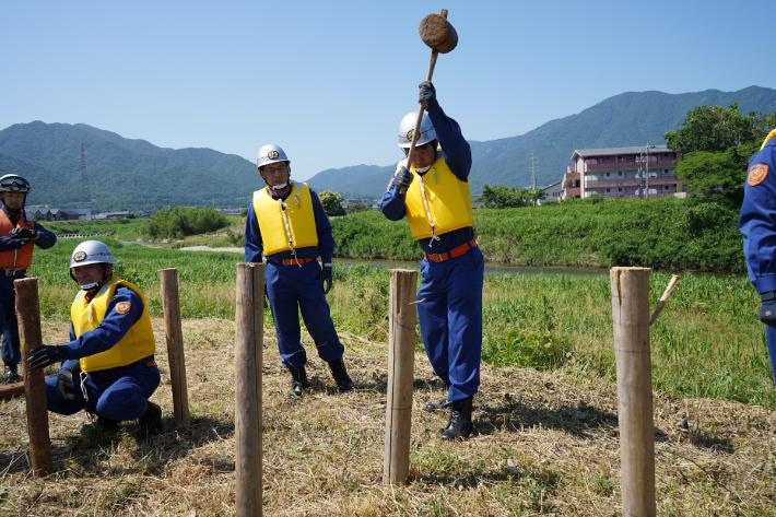 堤防に杭を打つ消防団員