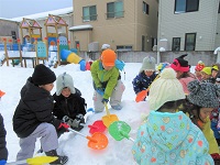 ぞう組がスコップを使って雪の滑り台をつくっています。