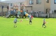 子ども達が、制作した鯉のぼりを持って園庭で遊んでいます。