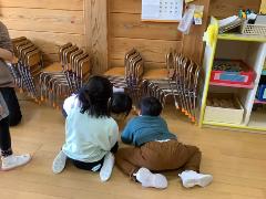 宝探しで子ども達がいすの下をのぞきこんで探しています。