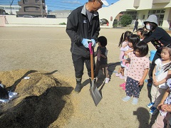 いちご組がさつまいもを火の中に入れています。