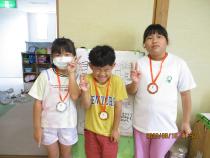 メダルをかけてピースサインをする3人の子供