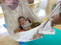 赤ちゃんが布ブランコで揺られている
