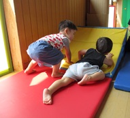 ホールでマットを使って運動遊びをしている子ども達の画像