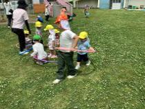 小さい子とフープで電車ごっこをしている画像