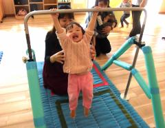 母親に支えられながら鉄棒にぶらさがる子どもの画像