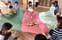 葉っぱが中に入った大きな布をゆらゆらさせているの画像