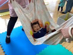 子どもが布ブランコで揺られている画像