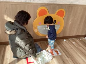 壁に貼ってあるくまの口にボールをつける男児