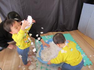 紙の素材の雪を頭上からほり投げている児の画像