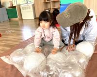 風船のマットに乗る女児と見つめる母の画像