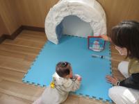 母が持つ雪だるまの玩具をみつめている女児