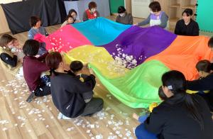 バルーンに紙の素材の雪を入れてみんなで揺らしている画像