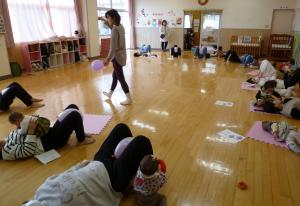 寝転がって講師の合図に合わせて風船を使ったストレッチをしているところです