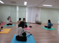 講師が腰に手を当て母親たちに説明する画像