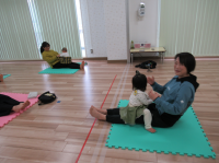 講師が女児を抱っこして座りストレッチをしている画像