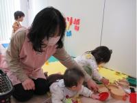 子育てボランティアと女児がおもちゃで遊んでいる画像