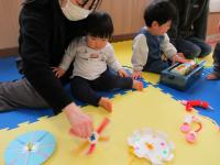 母が回すこまを見ている男児の画像