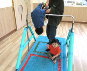 鉄棒で回っている兄と側にいる妹の画像