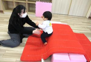 マットの山から母のところへ行く男児の画像