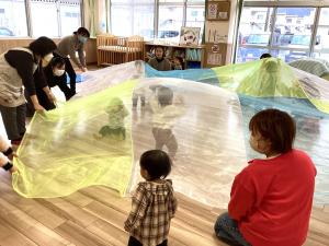 大きなオーガンジーの布の中にこどもたちが入っている画像