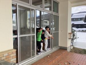 窓から外に向かって、豆をまいています