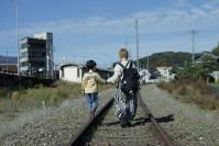 線路上を歩く親子の画像