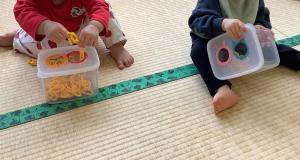 0歳児がチェーンを箱の穴に入れています