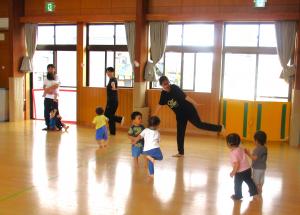 ホールでピアノの音に合わせて体を動かして遊んでいる写真