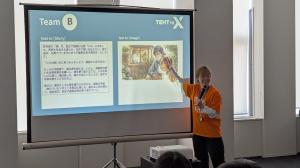 スライドを指しながら話している司会者の画像