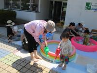 ジョーロで水あそびする親子の画像
