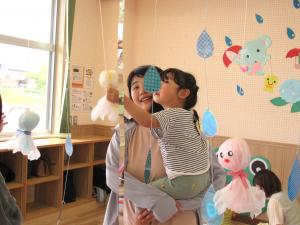 黄色のてるてる坊主に触れる女児の画像