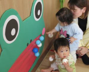 カエルの的あてのボールを指さす女児の画像