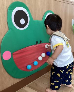 カエルの的あてからボールを外して片付ける男児の画像