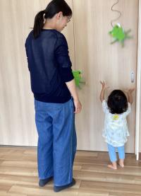 壁掛けのカエルの玩具が跳ねた様子を見ている女児の画像
