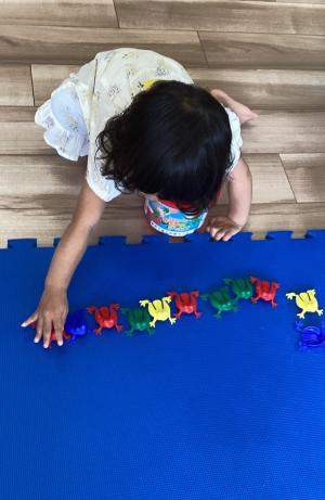 カエルの玩具を一列に並べる女児の画像