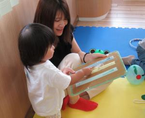 ファスナーの手作り玩具で遊ぶ女児と母の画像