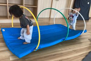 フープトンネルで遊ぶ女児の画像