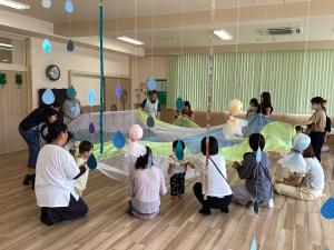 大きなオーガンジーの布をみんなで揺らす画像