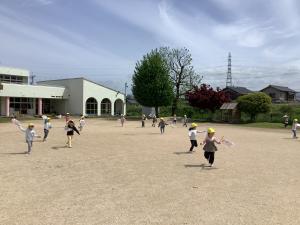 園庭で追いかけっこをする子どもたちの画像