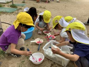 園庭の花で色水を作っている子どもたちの画像