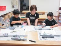 塩ビ管を接着剤で付けている兄妹の画像
