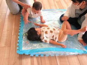 おおきなウォーターマットに寝転ぶ女児とそこに近づく女児の画像