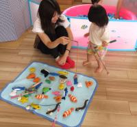 さかなつり遊びをする女児と母の画像
