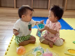 1つの玩具をつかむ男児と女児の画像