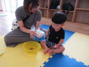 母と一緒に色水袋を触る男児の画像
